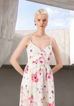 Vestido floral blanco con patrones en rosa y verde, tirantes tipo espagueti, corsé ajustado y falda acampanada. Tejido suave con una textura ligera.