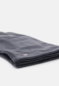 Navy blue scarf made of soft material, featuring a folded design and a small, rectangular logo tag with red and white accents.