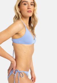 Light blue bikini set featuring a triangular bralette top and adjustable tie-side bottoms. Fabric is smooth with a minimal texture.