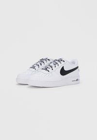 Λευκά χαμηλά αθλητικά παπούτσια από δέρμα με μαύρο λογότυπο swoosh, κορδόνια με υφή που έχουν γεωμετρικό μοτίβο και λαστιχένιες σόλες.