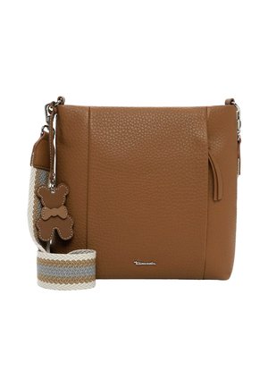 Brūna teksturēta ādas somiņa ar svītrainu auduma siksnu un mazu lāča rotaļlietas piekariņu uz balta fona.