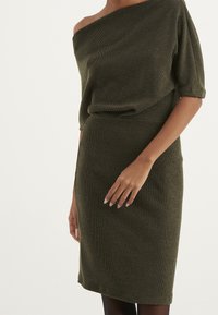 Grünes geripptes Strickkleid mit schulterfreiem Design und kurzen Ärmeln, figurbetont, glatte Textur, knielang und mit einem subtilen Taillenband.