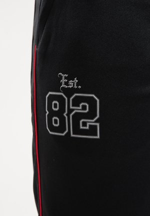 Black fabric featuring a white and grey embroidered "82" with "Est." above, accented with a red side stripe.