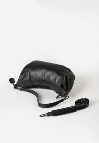 Zwarte leren schoudertas met een afneembare en verstelbare schouderriem, geplaatst op een witte ondergrond.