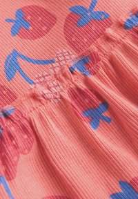Tissu rose côtelé avec une couture élastique, décoré d'un motif de fraises rouges et de feuilles bleues.