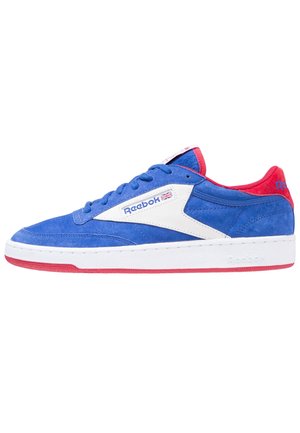 Blauer Wildleder-Reebok-Sneaker mit weißem Seitenpanel, roten Akzenten an Ferse und Sohle sowie britischem Flaggenlogo in der Nähe der Schnürsenkel.