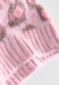 Tissu tricoté rose doux et duveteux avec une texture côtelée et des motifs floraux marron et rose foncé.