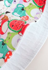 Cappello a secchiello in cotone con motivo colorato di animali in stile cartone animato sulla tesa, con fascia in tessuto bianco e dettagli di cuciture visibili.