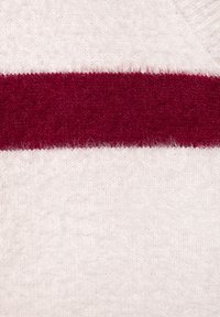 Gestrickter Stoff mit einem weißen Hintergrund und einem dicken burgunderroten Streifen. Weiche Textur mit sichtbaren Fasern, die ein gemütliches Erscheinungsbild erzeugen.
