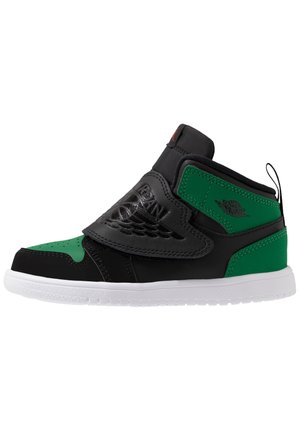 Zwarte en groene hoge sneaker met een glanzende leren bovenkant, geperforeerde neus en witte rubberen zool; heeft een klittenbandsluiting en een geperst logo.