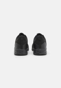 Black athletic shoes featuring a mesh upper, padded collar, pull tab, and rubber outsole with geometric pattern. Simple and functional design.