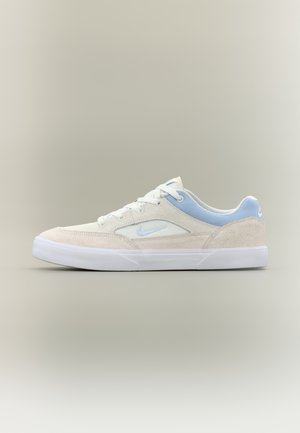 Buty sportowe Nike z beżową cholewką z zamszu, jasnoniebieskimi akcentami, białymi sznurowadłami oraz gumową podeszwą, prezentujące niski profil.