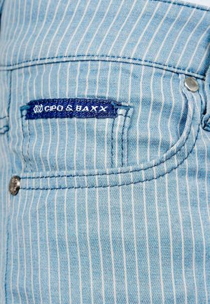 Lichtblauwe denim met witte verticale strepen, met een zaklabel in donkerblauw. Inclusief metalen knop en stikseldetails.