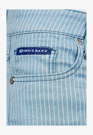 Lichtblauwe denim met witte verticale strepen, met een zaklabel in donkerblauw. Inclusief metalen knop en stikseldetails.