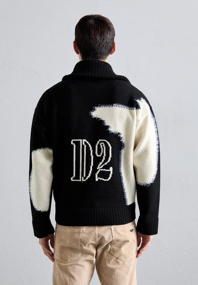 Zwarte trui met crème en blauwe accenten, voorzien van een chunky kraag en abstracte patronen. De achterkant toont "D2" in witte breiwerk.