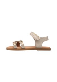 Flache Sandalen mit metallisch goldener Oberfläche, verziert mit einer dekorativen Schleife, offenen Seiten und verstellbarem Riemen für eine optimale Passform. Texturiertes Fußbett und Gummisohle.