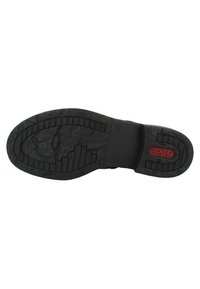 Semelle de chaussure en caoutchouc noir avec un motif texturé, mettant en valeur un accent de logo rouge et un motif en couches pour une meilleure adhérence. Plate avec des bords arrondis.
