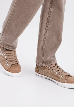 Sneakers high-top beige in tela con suole in gomma bianca, lacci piatti e dettagli di cucitura. Indossati con pantaloni tapered beige.