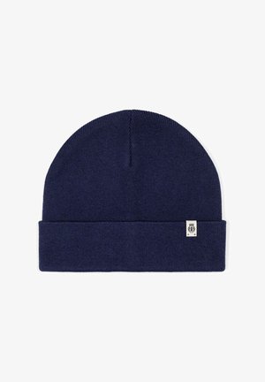 Navy blue knit beanie with folded cuff and small white rectangular tag featuring a black emblem on the cuff's lower edge.