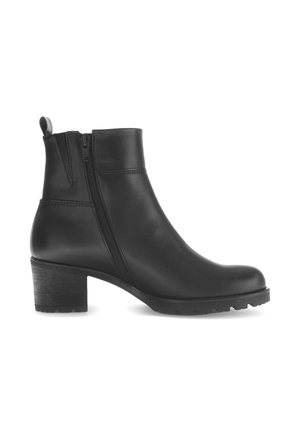 Zwarte lederen enkelboot met zijkit, trekband, ronde neus en chunky lage hak op een witte achtergrond.