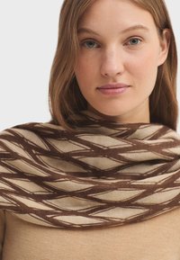 �Écharpe en tissu tissé présentant un motif en diamant dans des tons marron et crème, avec une texture lisse et un design drapé polyvalent.