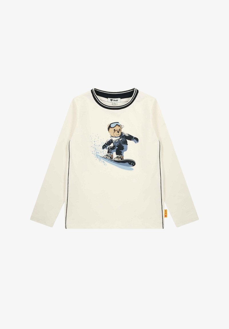 Camicia a maniche lunghe color crema con rifiniture nere, caratterizzata da una grafica di un orso che fa snowboard. Tessuto morbido, vestibilità casual, orlo cucito, dettaglio con etichetta arancione.