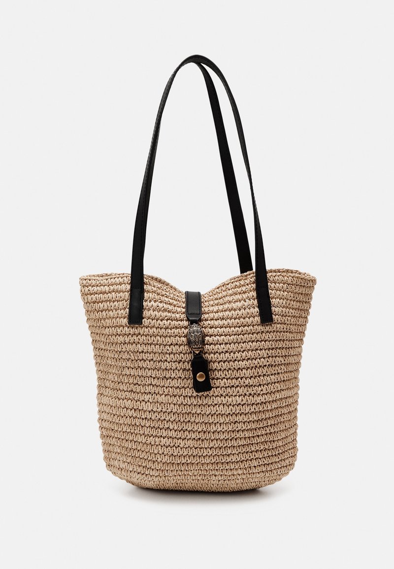 Sac fourre-tout en paille tissée beige avec de longues anses en cuir noir et un fermoir décoratif en cuir noir orné d'un détail métallique au centre supérieur.