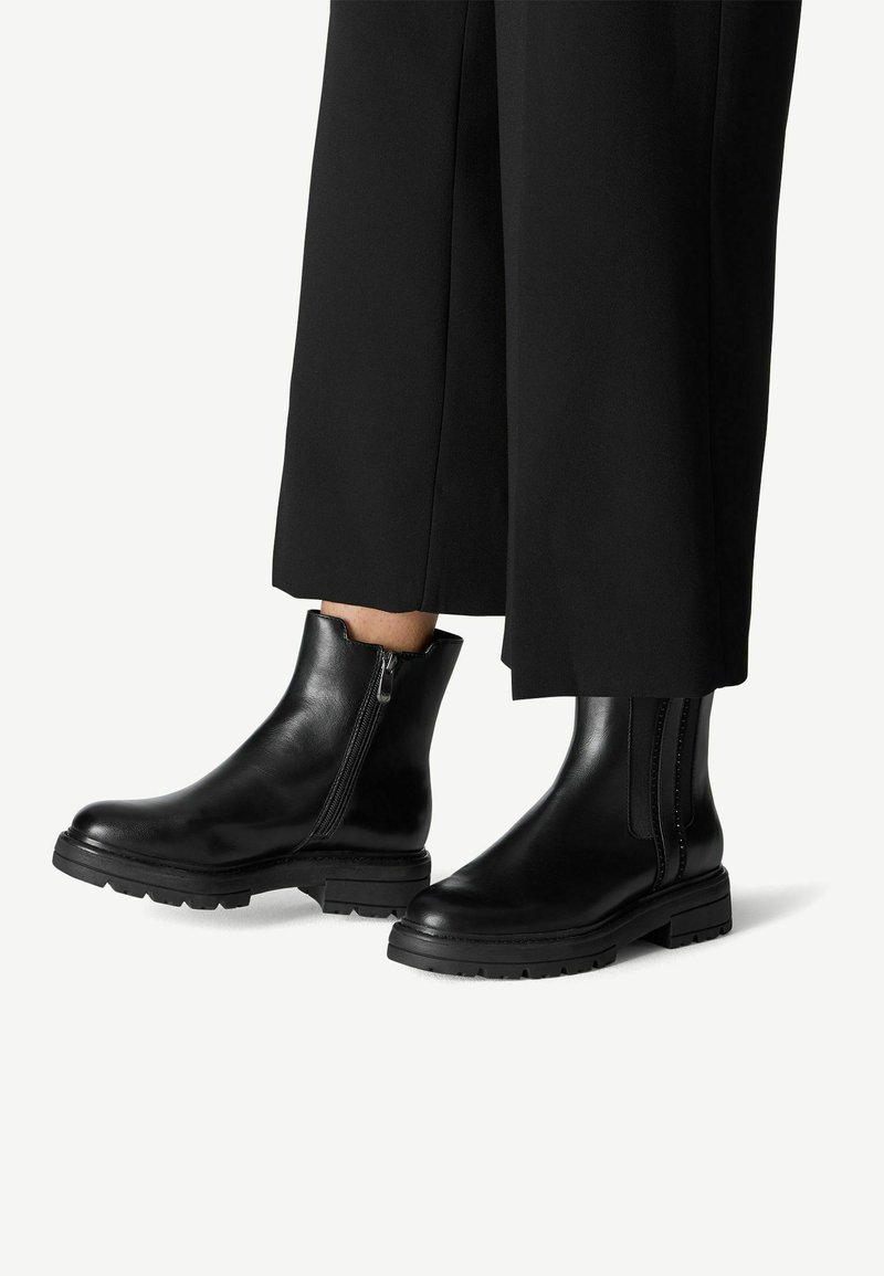 Bottines en cuir noir avec un design élégant, des fermetures éclair sur les côtés, des semelles épaisses et une texture lisse. Conviennent à diverses tenues.