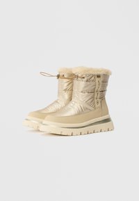 Padded beige winter boots with faux fur trim, featuring a textured upper, sturdy rubber sole, and contrasting accents for style and durability.
