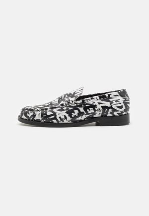 Czarno-białe mokasyny typu slip-on z abstrakcyjnym wzorem w stylu graffiti i niskim obcasem, pokazane z boku na jednolitym tle.