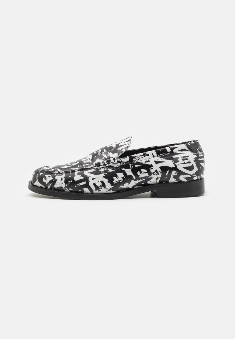 Mocassin slip-on noir et blanc avec motif abstrait style graffiti et talon bas, présenté de profil sur un fond uni.