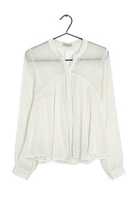 Vit blus med långa ärmar, genomskinlig frontpanel, knappstängning och rundad krage. Lättviktsmaterial med en flödande, lager-på-lager design.