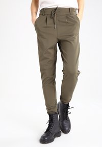 Olijfgroene broek met een trekkoord in de taille, geplooid voorpand, slim fit, en gecombineerd met zwarte veterschoenen. Glad, lichtgewicht stof.