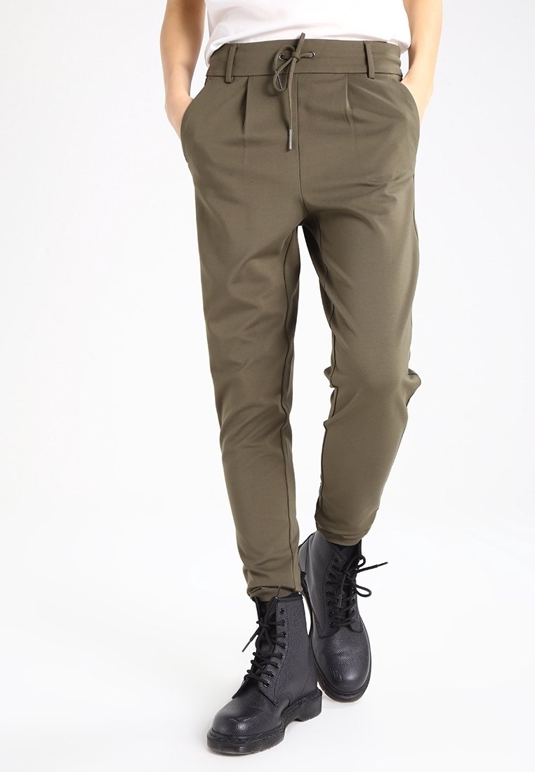Olive zielone spodnie z elastycznym pasem, plisowanym przodem, slim fit, w połączeniu z czarnymi sznurowanymi botkami. Gładki, lekki materiał.