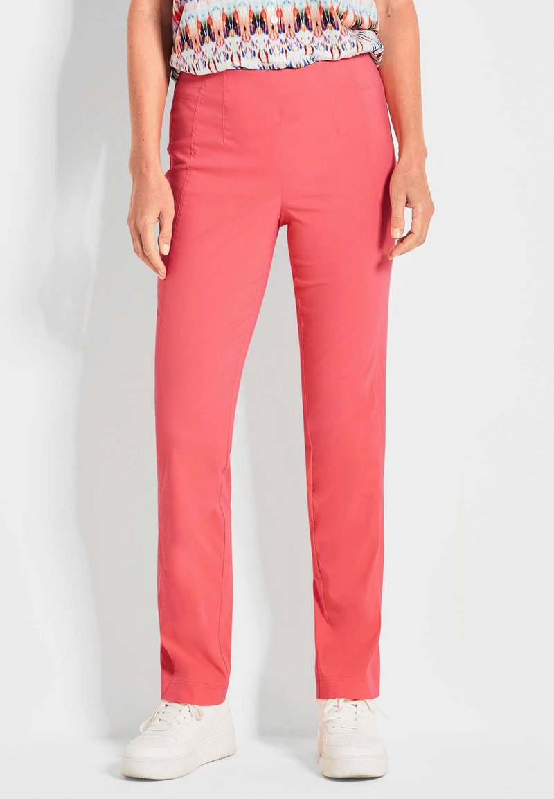 Pantalons roses ajustés avec une texture lisse, coupe slim et poches latérales. Assortis à des baskets blanches pour un look décontracté.