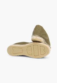Groene geweven espadrille met een gestructureerde stof, beige gevlochten touwafwerking en een flexibele rubberen zool. Heeft een hartvormig loopprofiel.