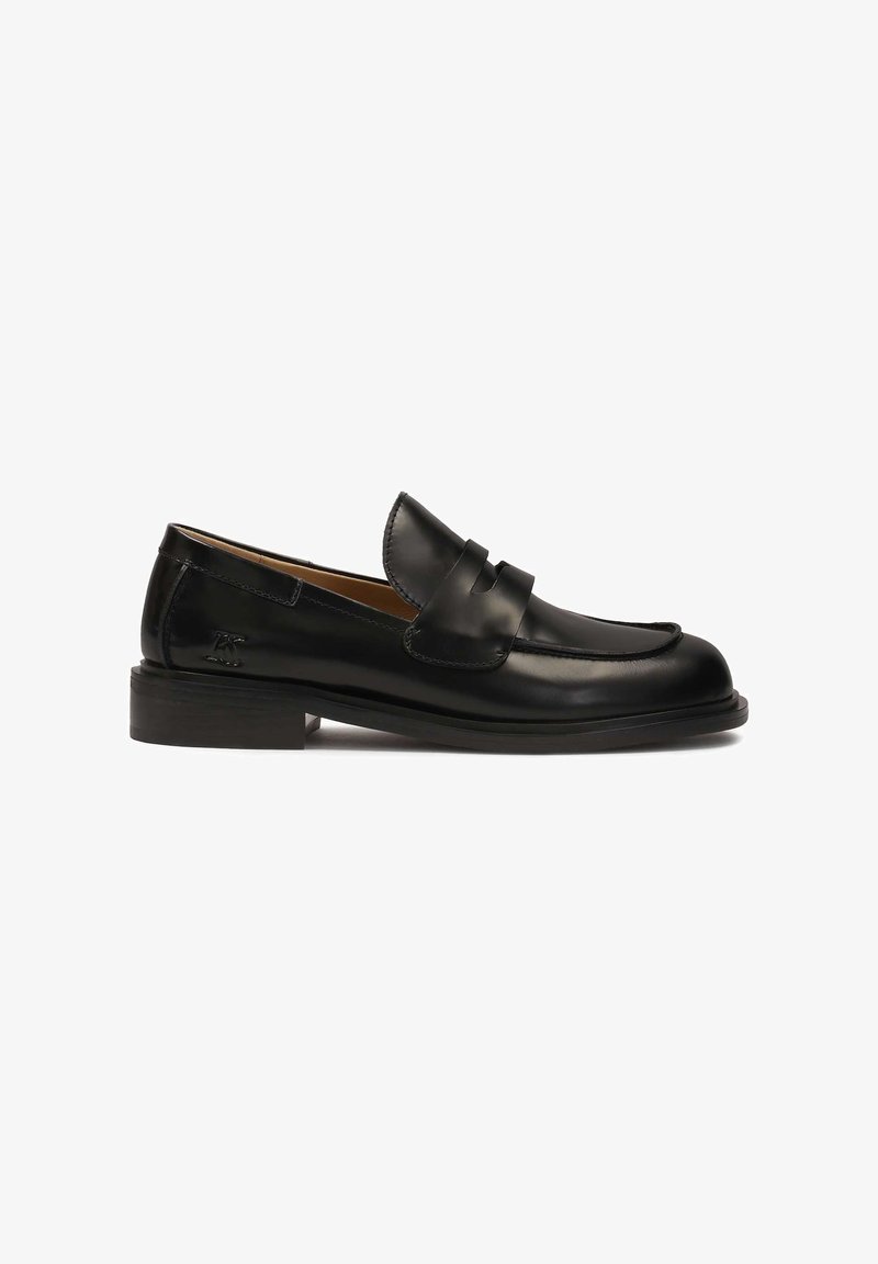 Black leather loafer with a rounded toe, decorative upper strap, and low stacked heel. Smooth texture and minimal stitching details.