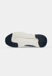 Semelle de chaussure avec une bande de roulement en caoutchouc noir et blanc, avec des motifs ondulés antidérapants et le nom de la marque "Marc O'Polo" embossé au centre.
