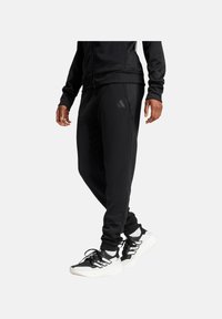 Schwarze Sportleggings verfügen über ein tailliertes Design, einen elastischen Bund und Seitentaschen. Ein dezentes, dreieckiges adidas-Logo ist auf dem Oberschenkel geprägt.