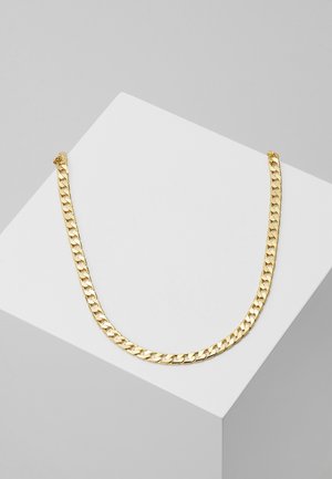 Naszyjnik z łańcuszka curb w kolorze złotym, prezentowany na białej, kanciastej powierzchni na jasnoszarym tle.