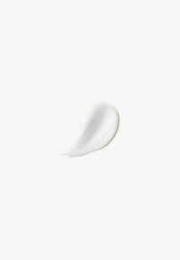 Substance blanche ressemblant à une crème, avec une texture lisse et brillante, appliquée en forme courbée sur un fond uni. Aucun motif ni matériel.