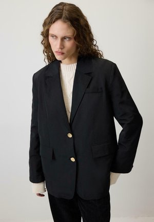 Mustيغmusti blazer, millel on kohandatud sobivus, kullatud nuppe, kaks esimest taskut, kantud koorevärvi koonuslõngast kampsuni peal. Sile tekstuur, struktureeritud disain.