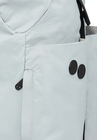 Hellblauer Stoffrucksack mit einem Reißverschlussfach, zwei schwarzen runden Knöpfen und einem kontrastierenden schwarzen Reißverschlusszieher. Texturierte Oberfläche mit Karomuster.