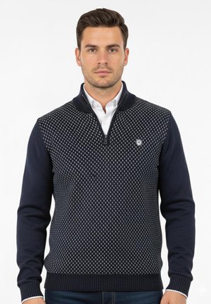 Suéter de punto de marina con cuello de media cremallera, patrón de tejido texturizado y mangas ajustadas. Presenta un pequeño logo en el lado izquierdo del pecho.