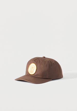 Gorra de béisbol marrón con visera curva y parche amarillo redondo con una palmera y el logo de "Billabong" en el panel delantero.