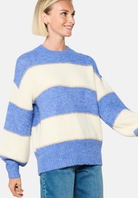 Sinine ja kreemjas triibuline kampsun, millel on tekstureeritud kudumus, soonilised mansetid ja äär. Omab ümarat kaelust ning laiad, lõtvad varrukad.