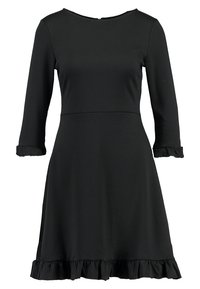 Robe noire avec un corsage ajusté, des manches trois-quarts et un ourlet à volants. En tissu lisse, avec un col rond et une fermeture éclair au dos.