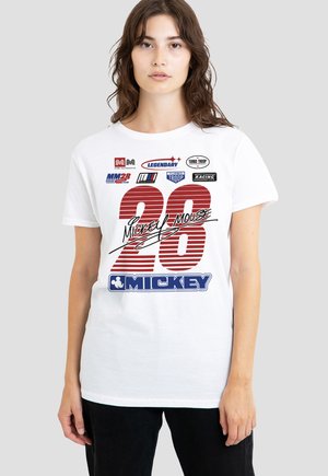 Junge Frau mit weißem T-Shirt, auf dem in Rot die Zahl "28", in Schwarz der Schriftzug "Mickey Mouse" sowie verschiedene rennsportbezogene Logos in Blau, Schwarz und Rot abgebildet sind.