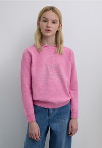 Pink sweater made of soft material featuring a rhinestone skull and crossbones design, with a crew neck and ribbed cuffs and hem.