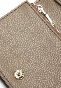 Portafoglio in pelle marrone con superficie texturizzata, zip argentata e dettagli in metallo dorato. Design compatto e rettangolare.